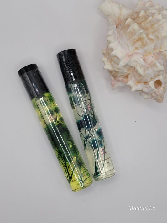 two decorative roller bottles with black tops and cuticle oil infused with dried plants in them.
