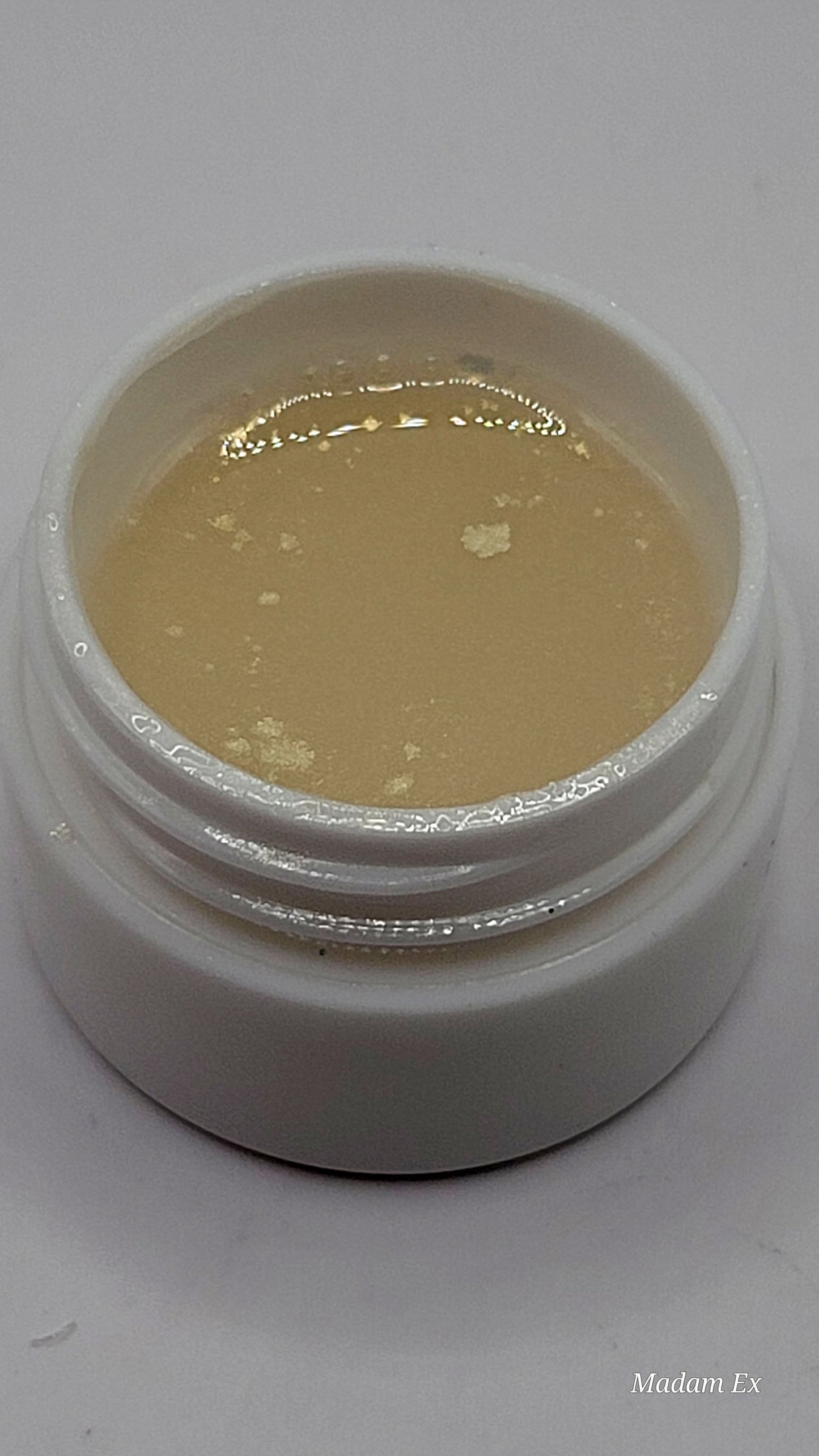 uv jar opened with beige uv hard gel on a gray background partial top view