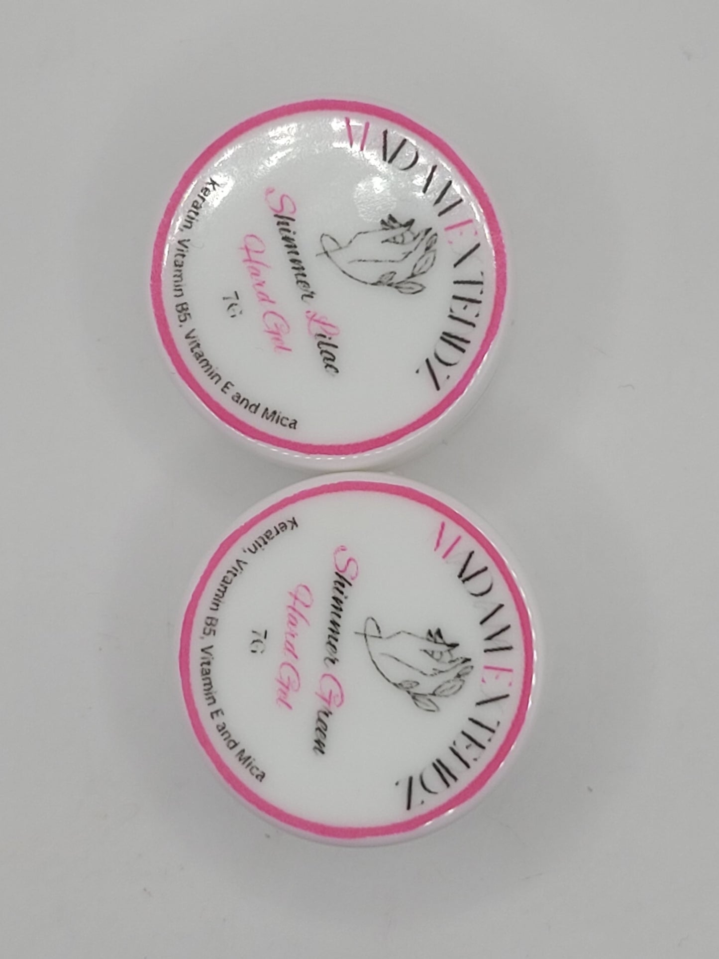 Two small uv containers with white lids and pink writing on a gray background