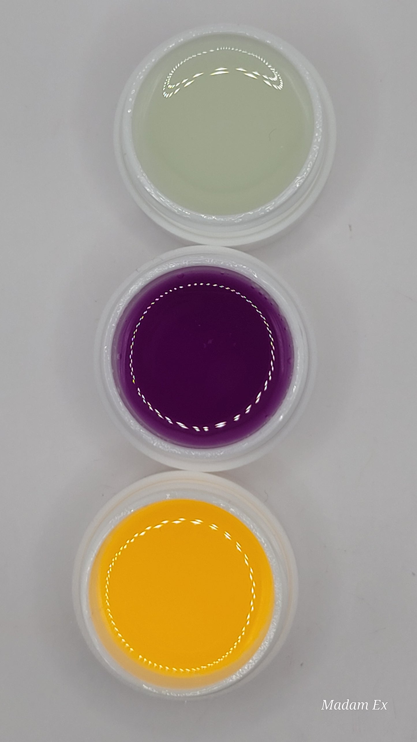 Three UV hard gels: clear, purple, and orange, on a white background.