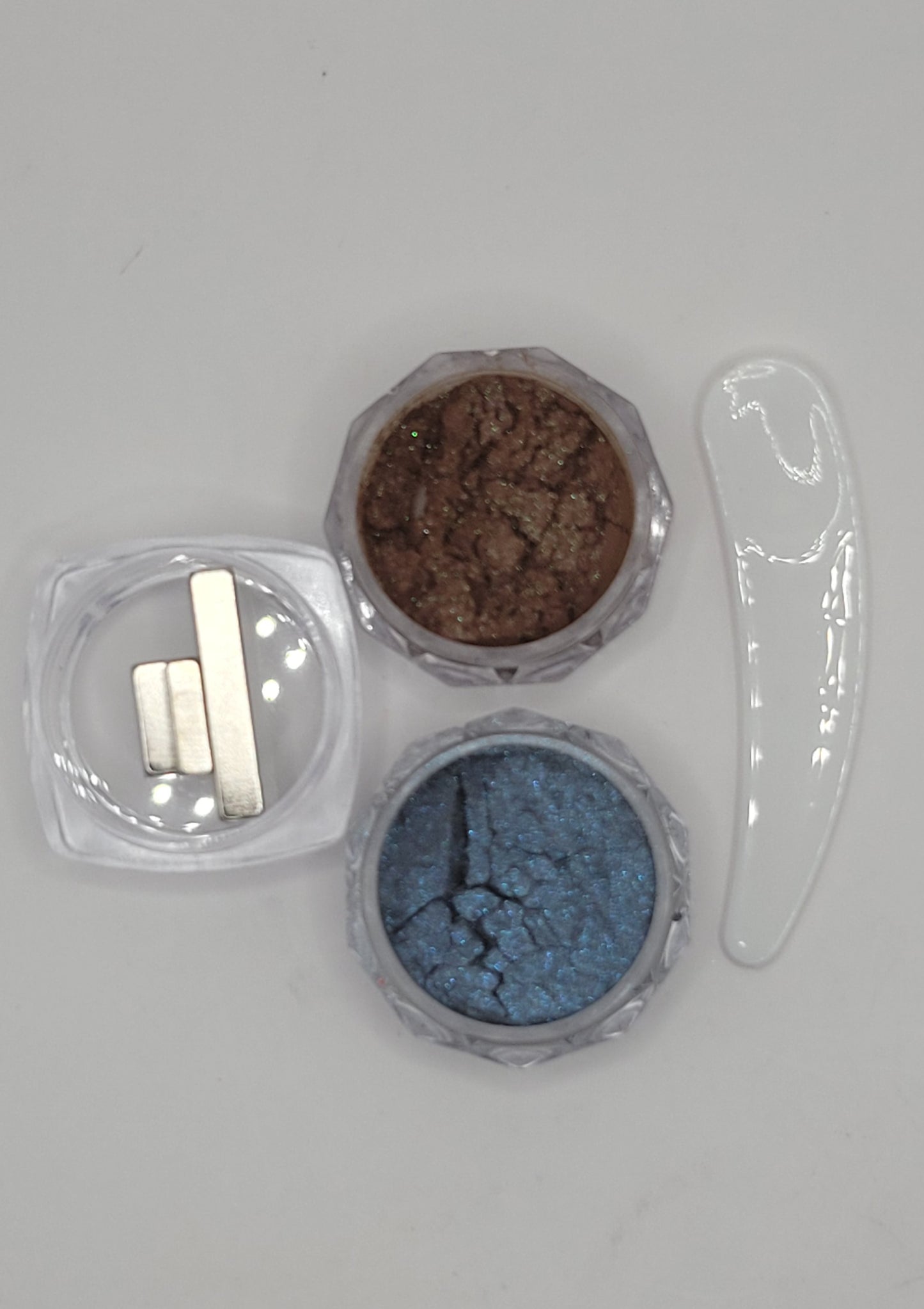 two small containers with cat-eye chameleon powder mix in a clear plastic containers on a white background brown and blue with a scoop and 3 mini magnets