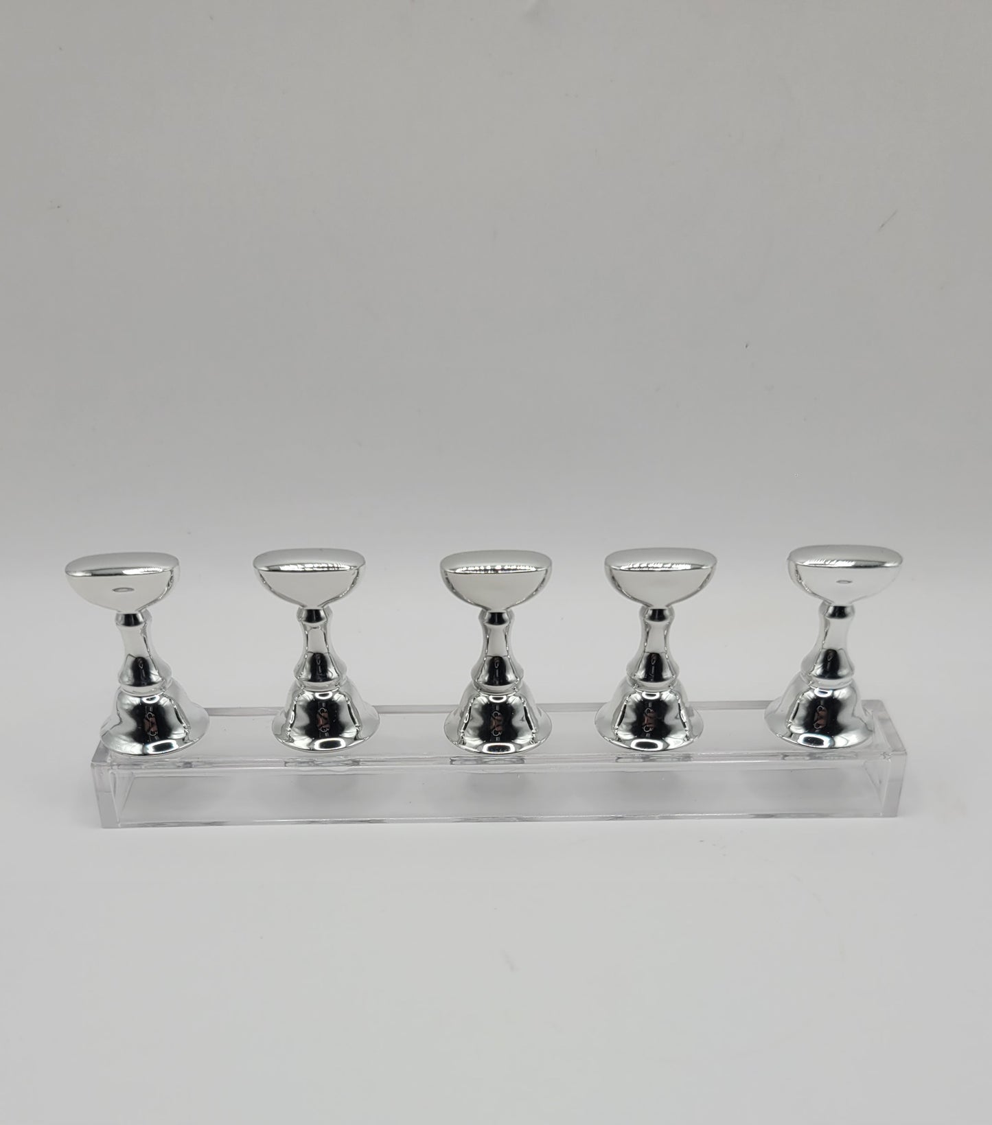 1 Set of five silver nail display stand on a clear stand against a gray background