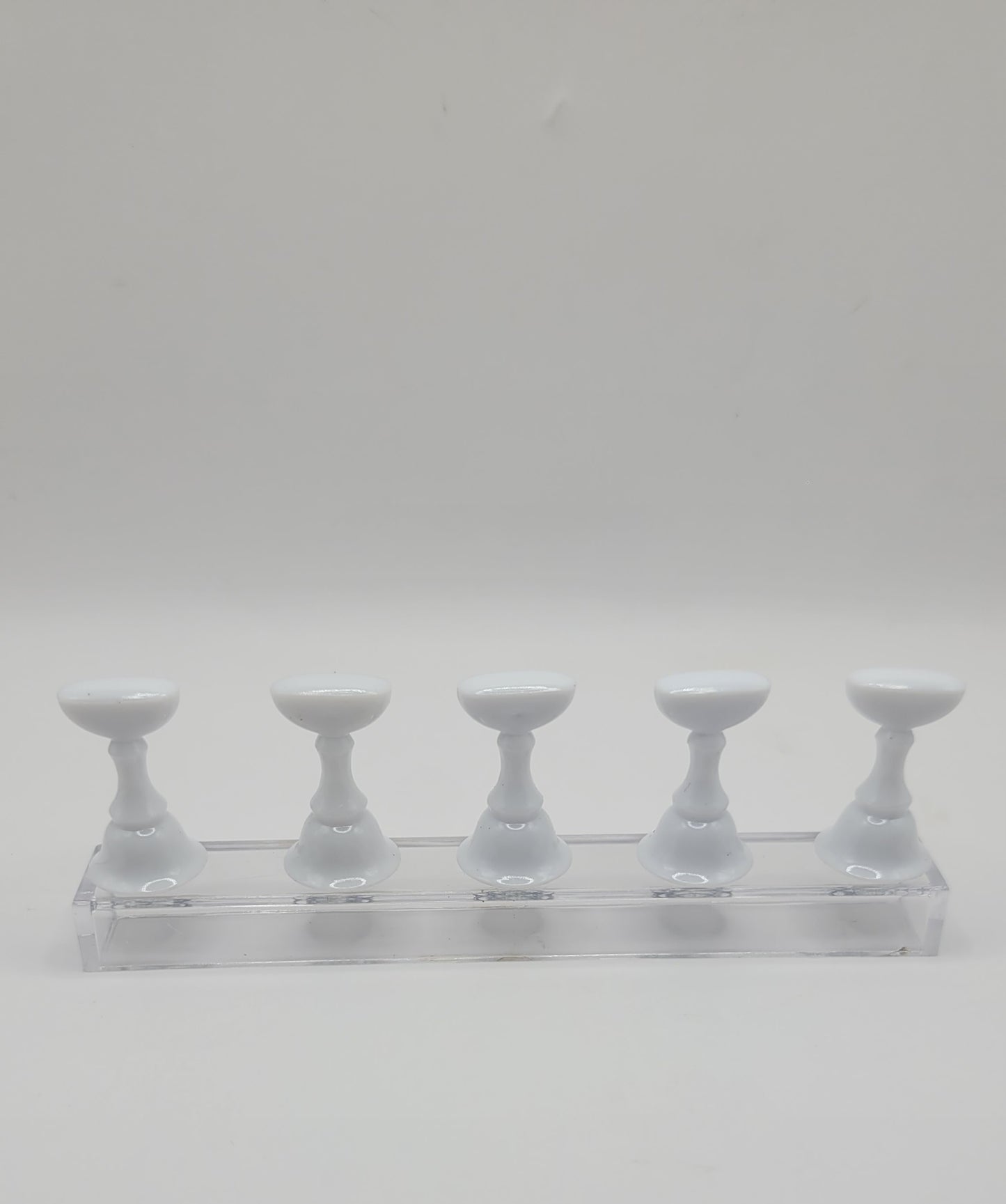 1 Set of five white nail display stand on a clear stand against a gray background