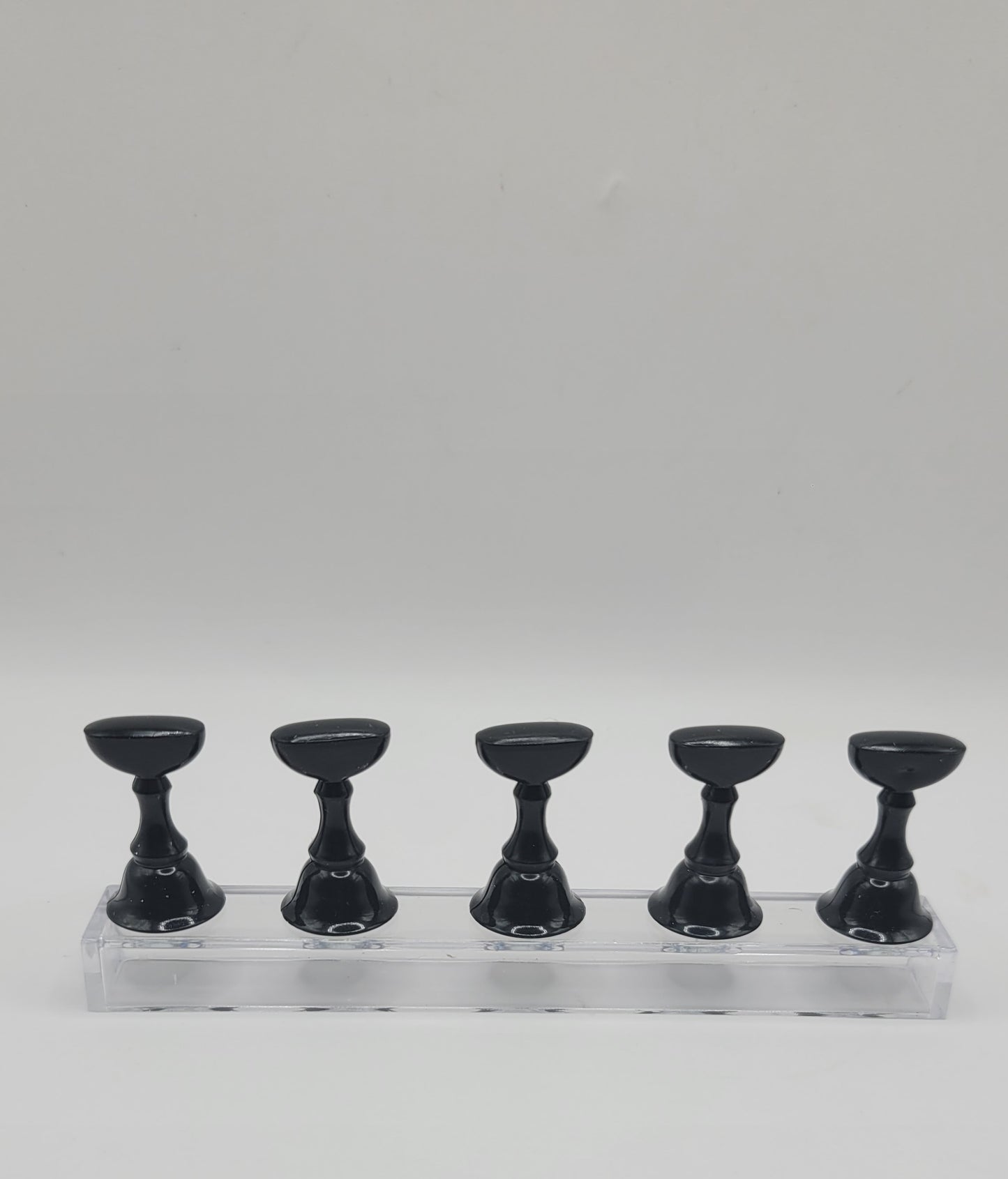 1 Set of five black nail display stand on a clear stand against a gray background