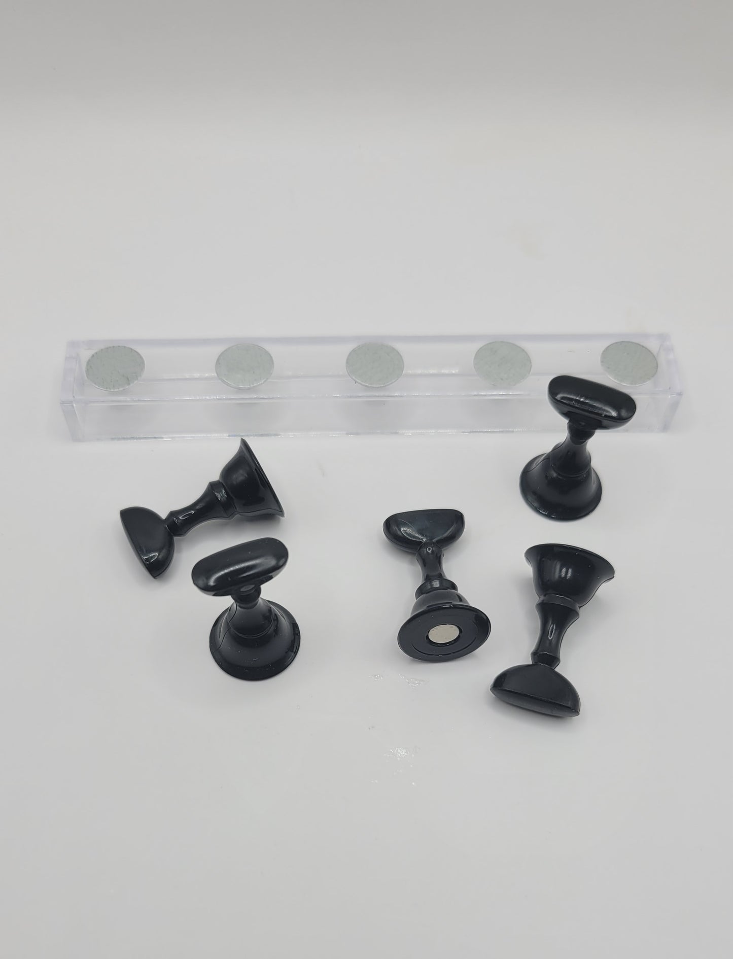1 Set of five black nail display pieces laying next to clear stand on against a gray background