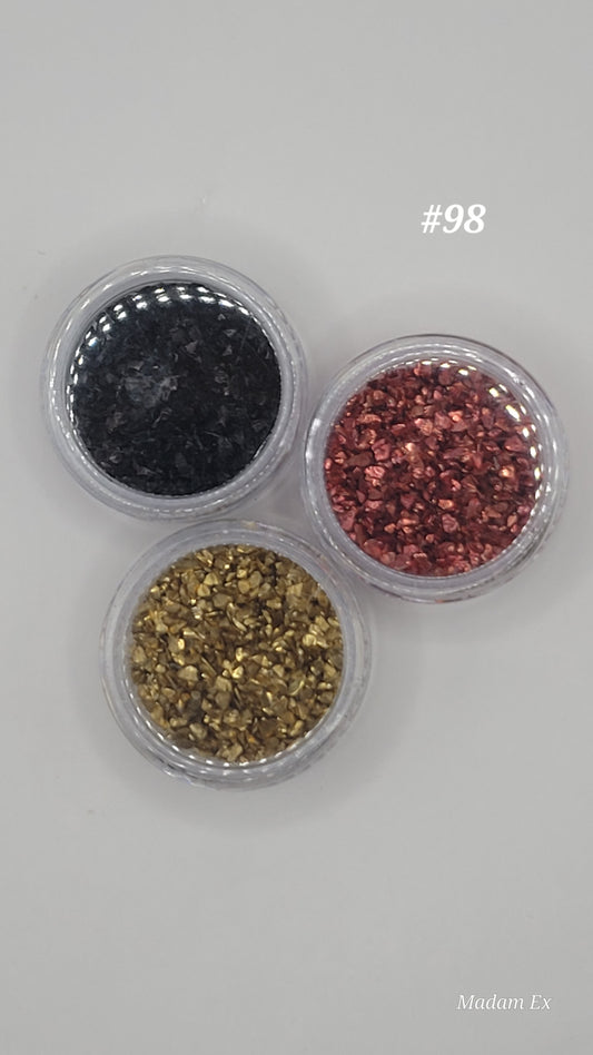 Three small containers of crushed glass in black, red, and gold on a light gray background.