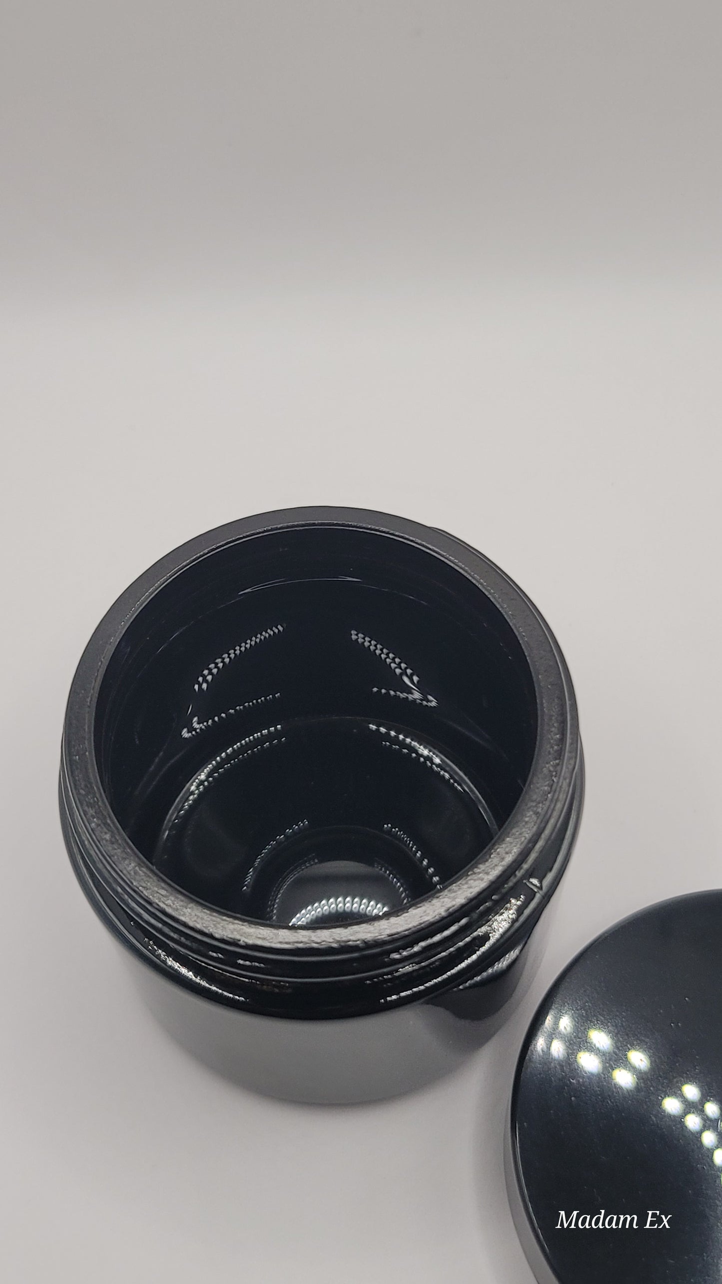 black jar with lid off laying next to it with a view of the inside