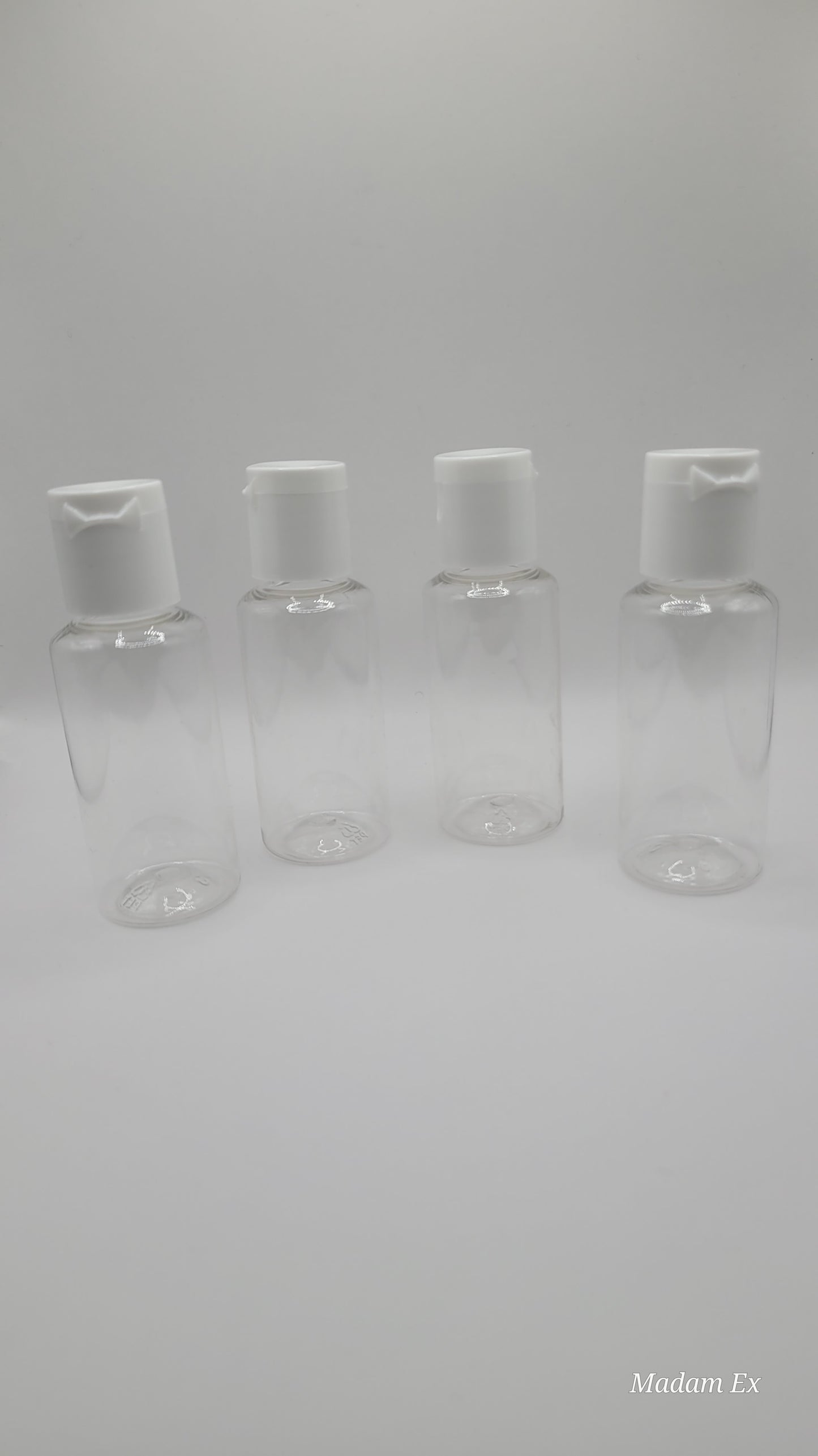 four clear plastic bottles with white tops on a gray background