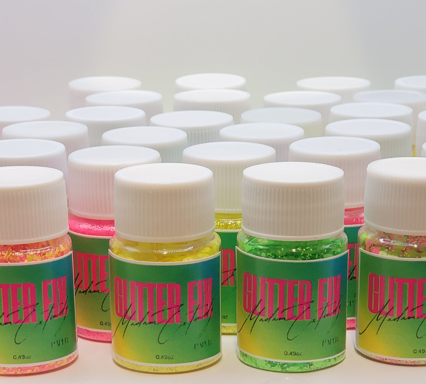 a group of Glitter Fix glitter with green label and pink contents on a white background