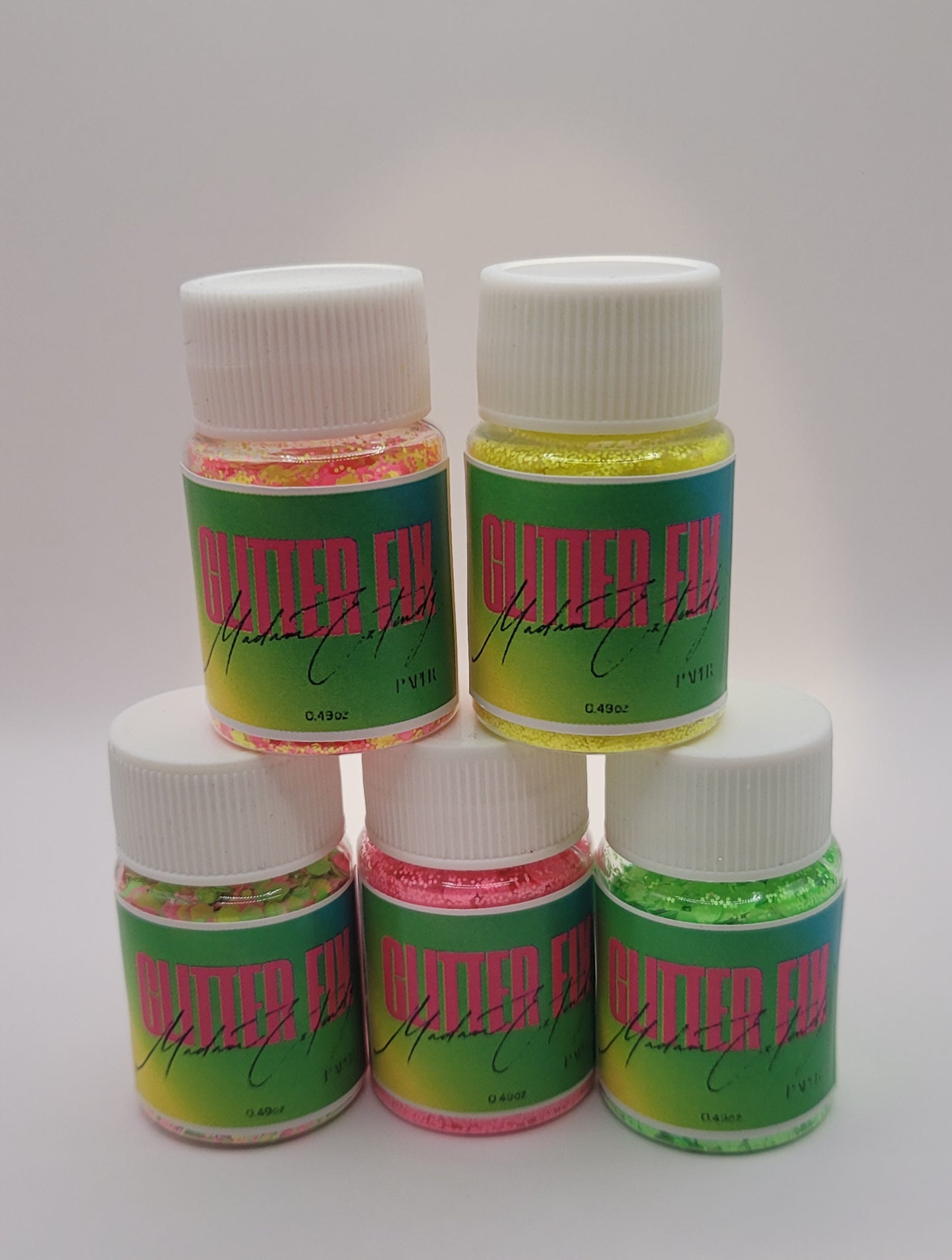 five bottles of Glitter Fix with green label and pink contents two stacked on top of three on a white background