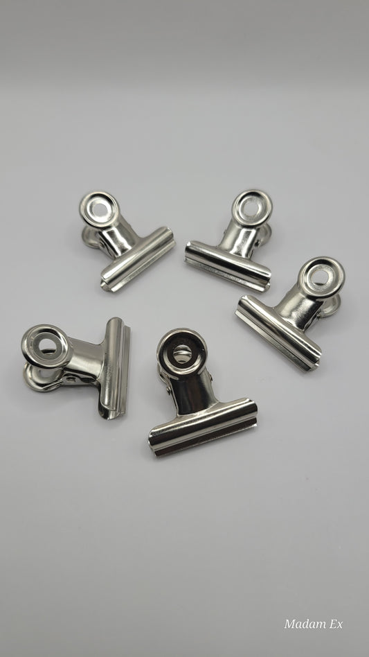 5 stainless steel nail clips on a white backround