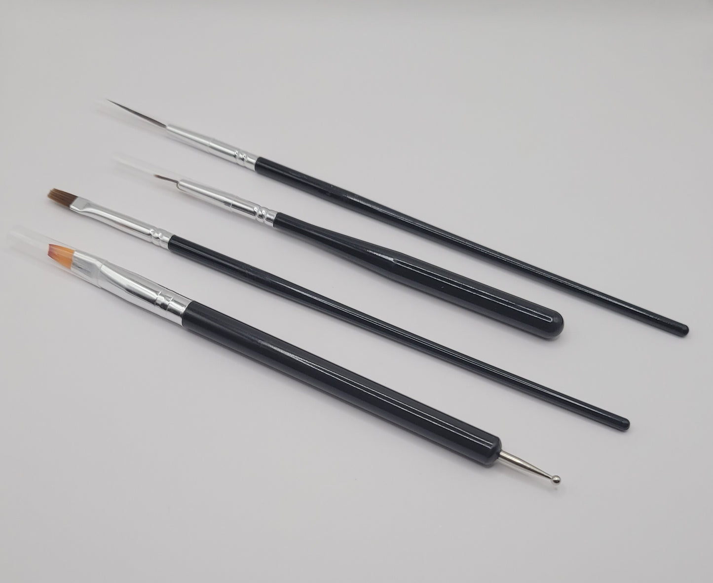 five black and silver nail art brushes on white background