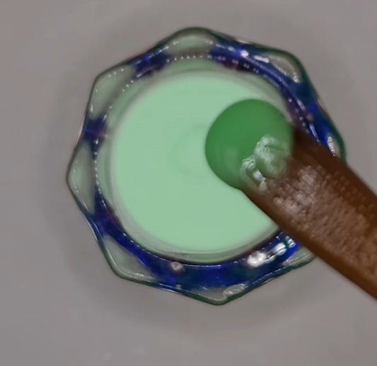 green neon acrylic poder in dappen dish on a acrylic brush with white background