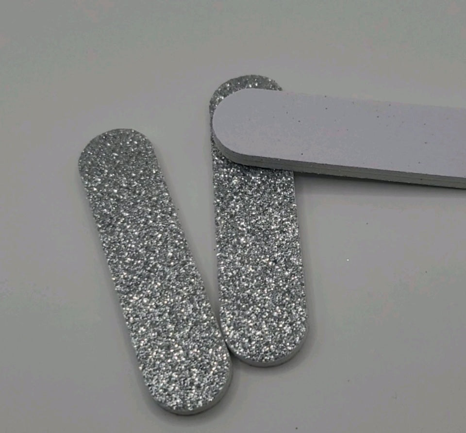 three glittery silver nail file on a light gray background