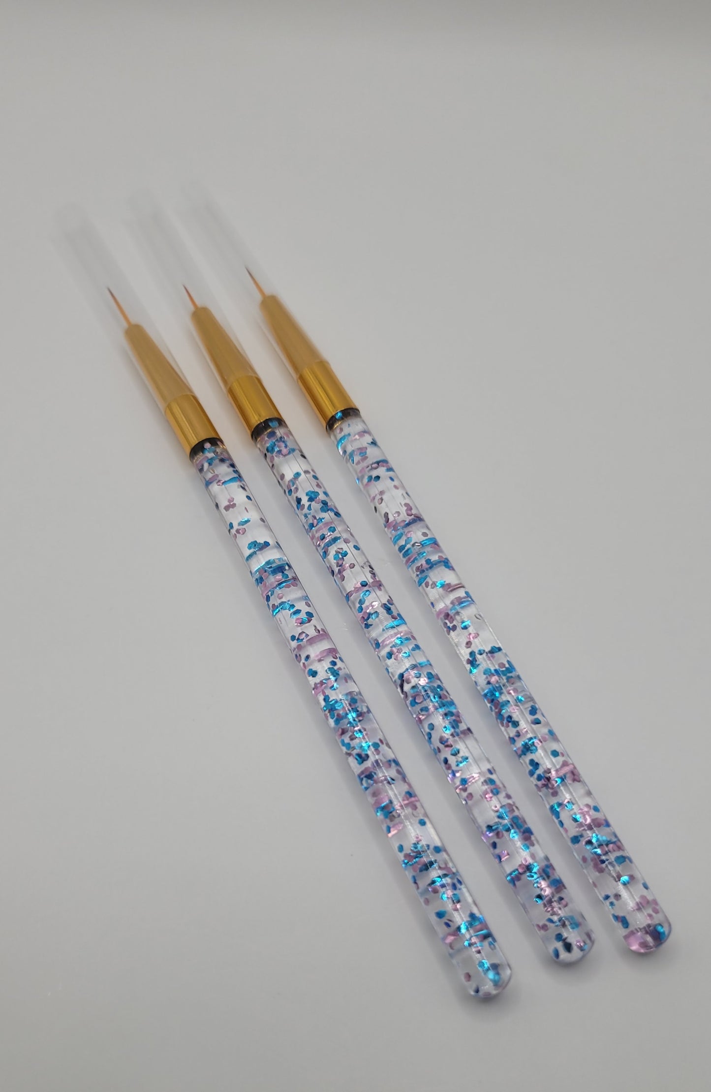 three nail art brushes on white background