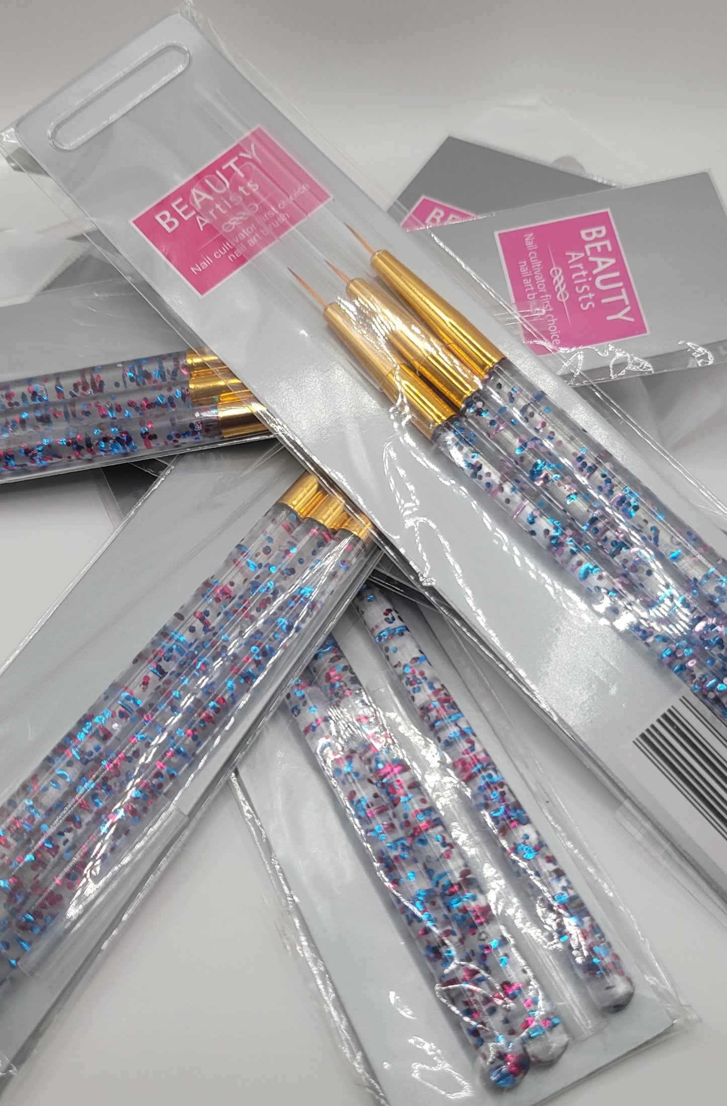 five packs of nail art brushes in a pile on a white background