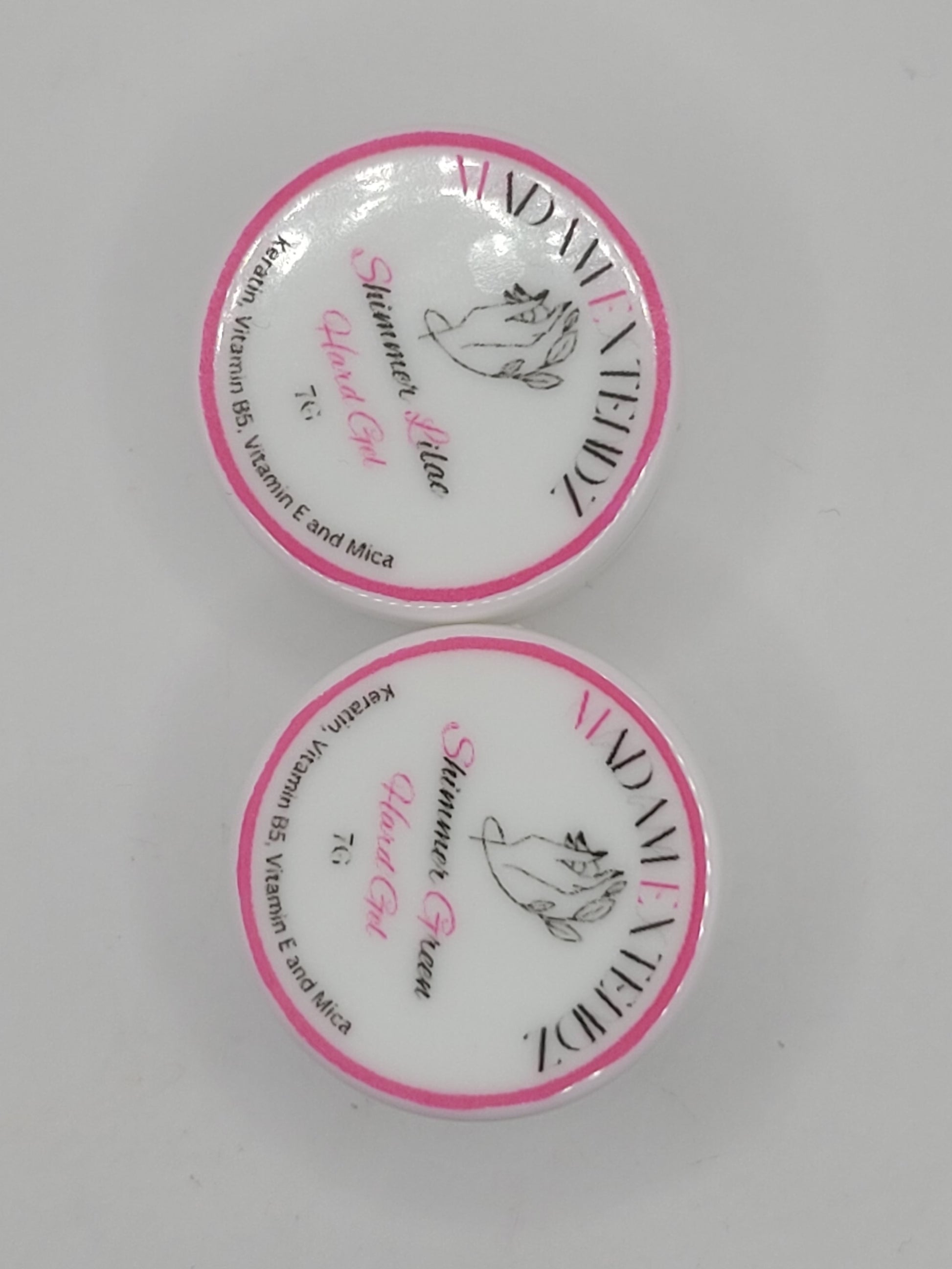 Two small uv containers with white lids and pink writing on a gray background