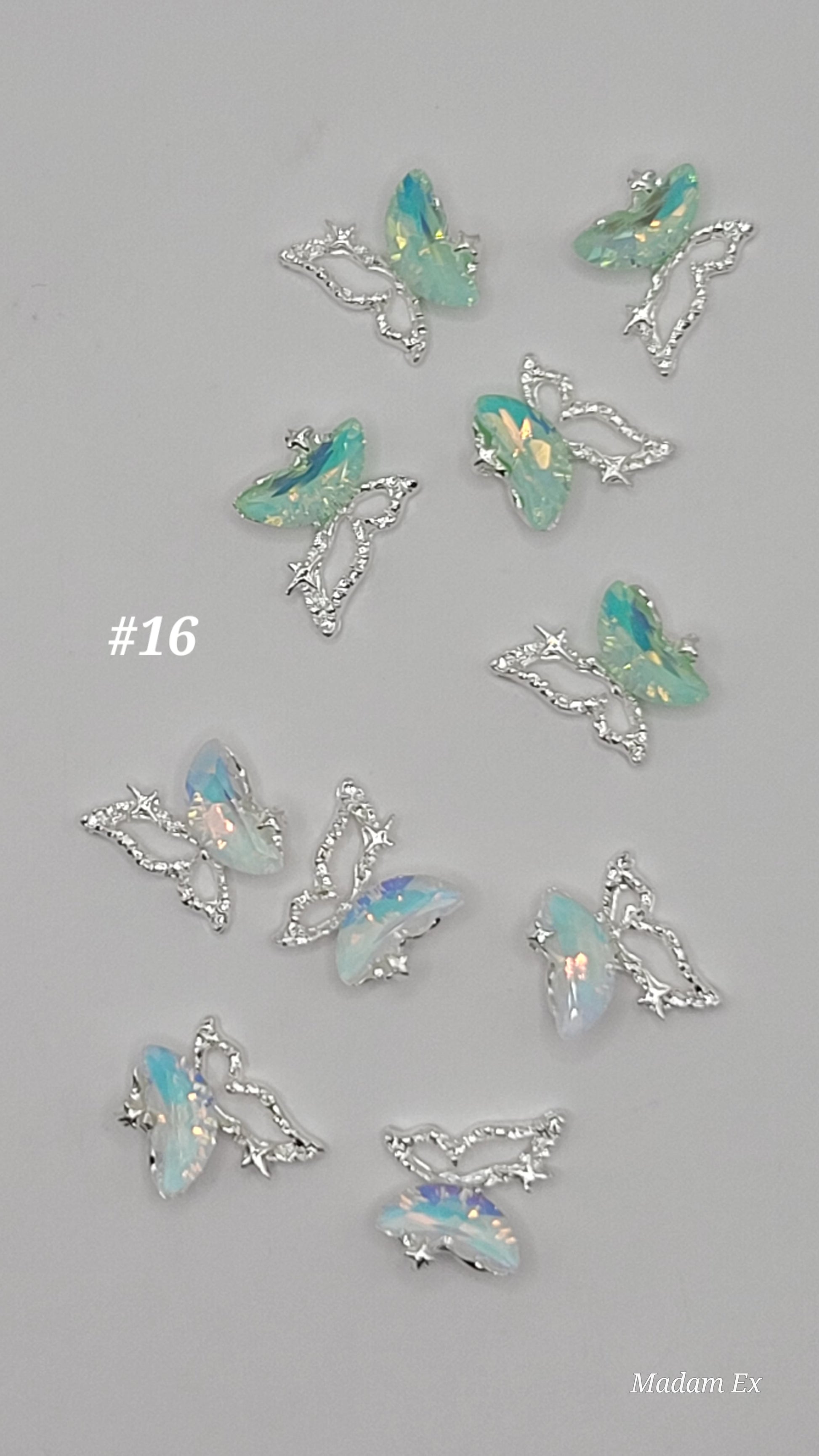 10 Silver butterfly-shaped jewelry pieces with opal-like stones on a gray background