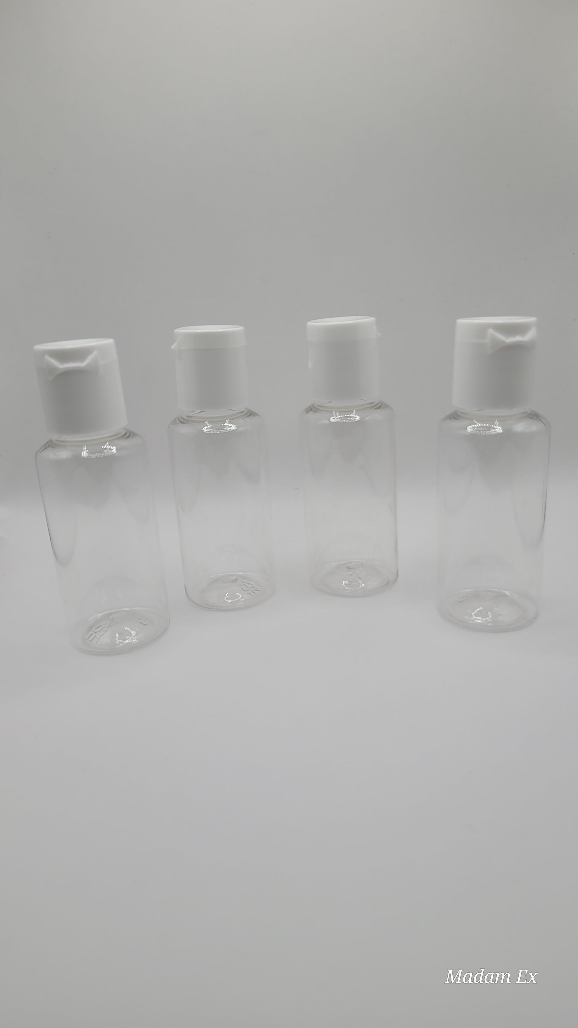 four clear plastic bottles with white tops on a gray background