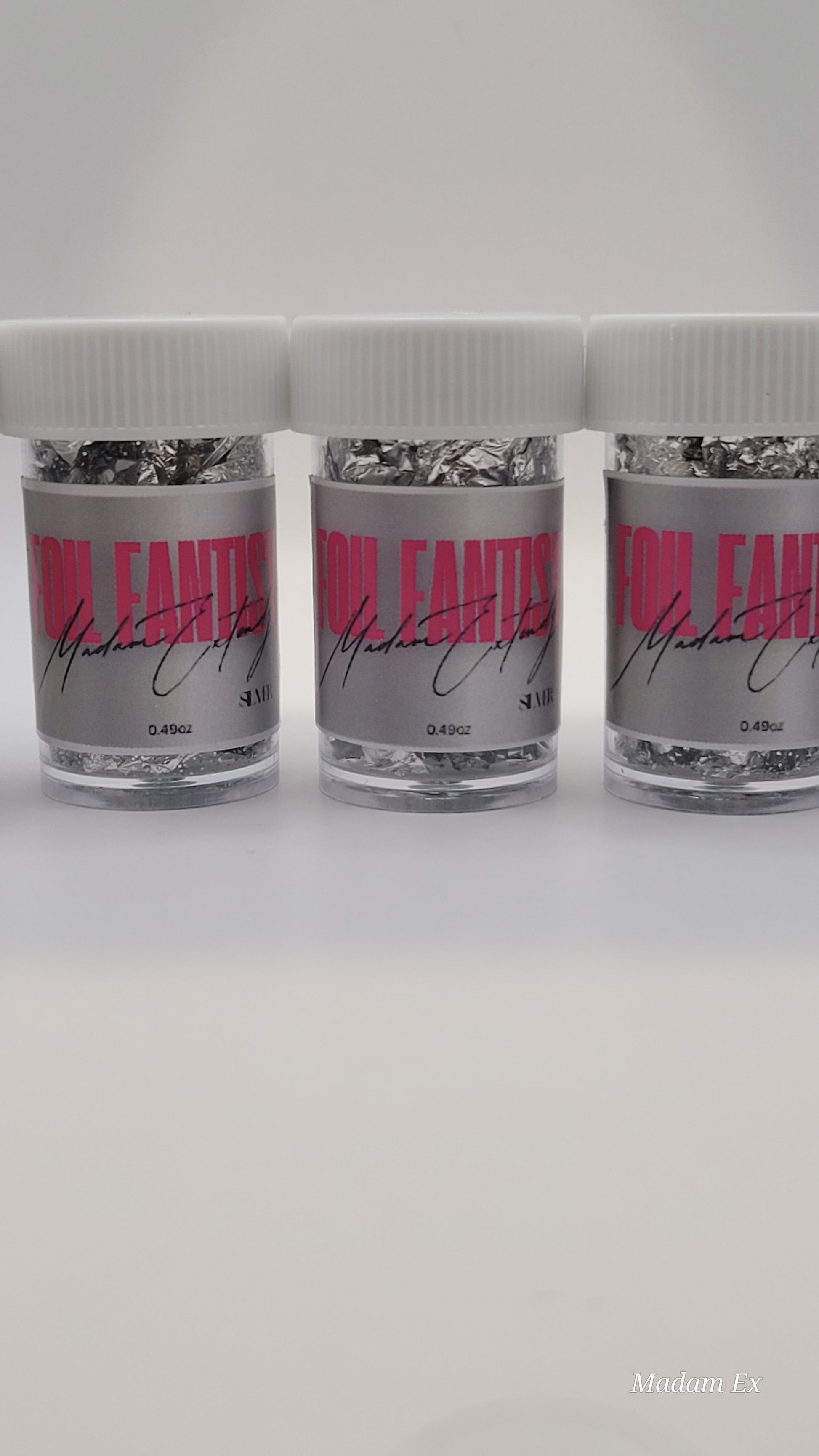 Three containers of silver foil fantasy with pink labels on a white background