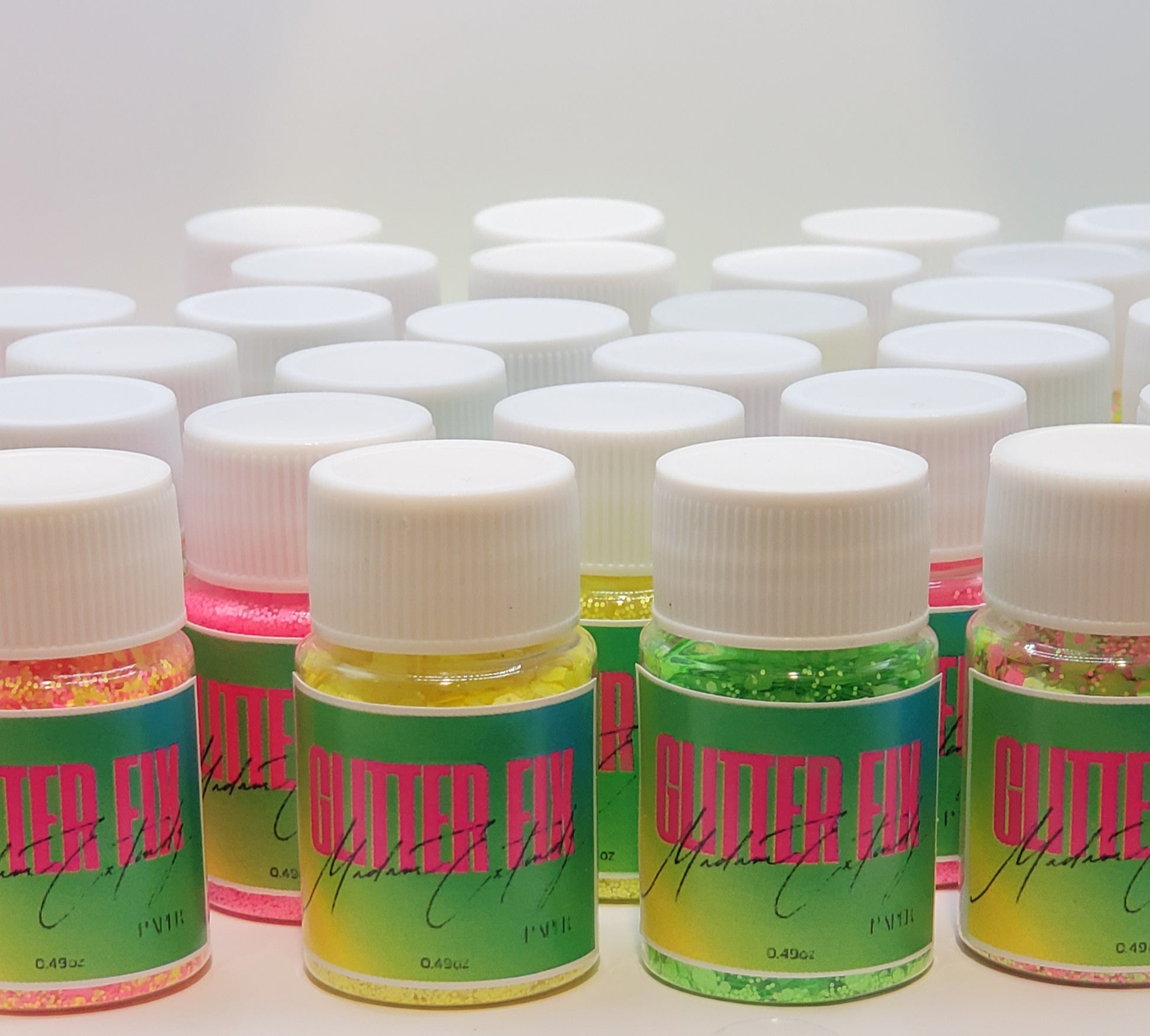 a group of Glitter Fix  glitter with green label and pink contents on a white background