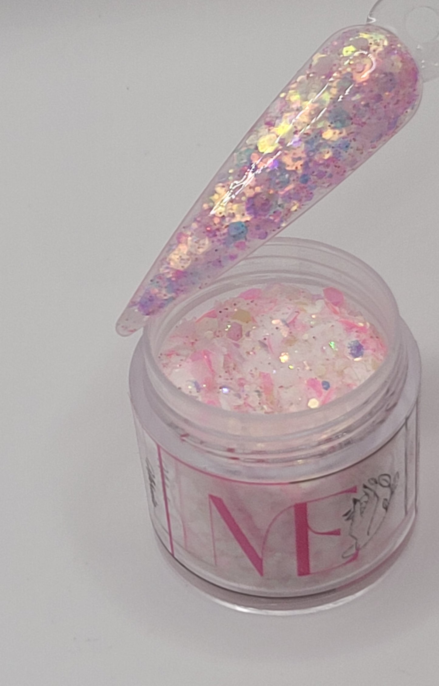 pink glow in the dark Iridescent glitter acrylic in a jar with  a swatchstick over top against a light gray background
