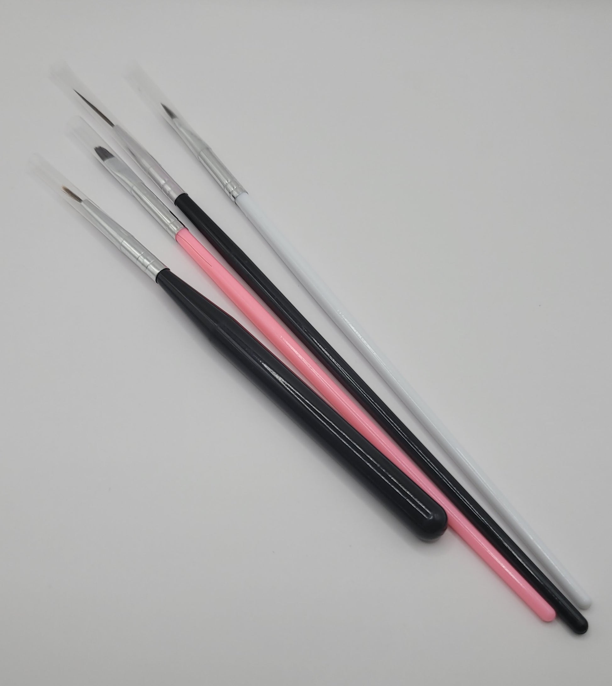 four piece 2 black and silver, 1 pink, 1 white nail art brushes on white background