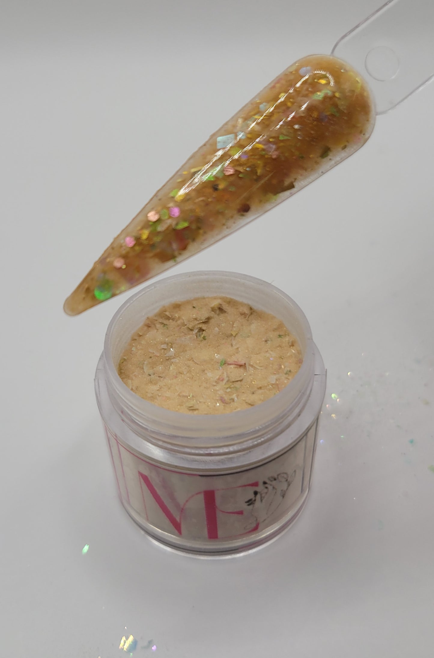 open Jar of orange decorative glitter foil acrylic mix top opened with a swatch stick over top on a white background