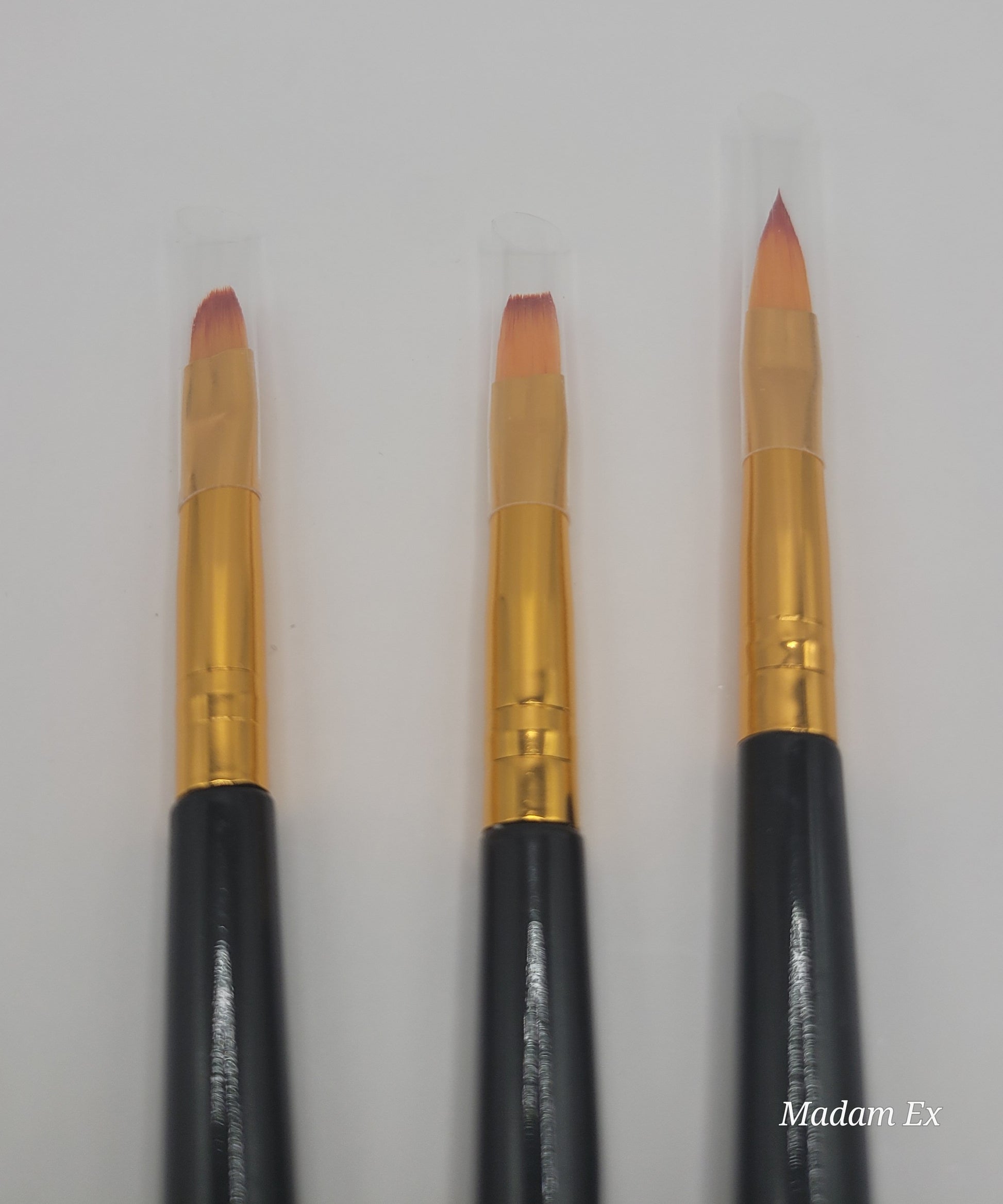 close-up view of three small,medium, large dual end black and gold nail art brush on white background